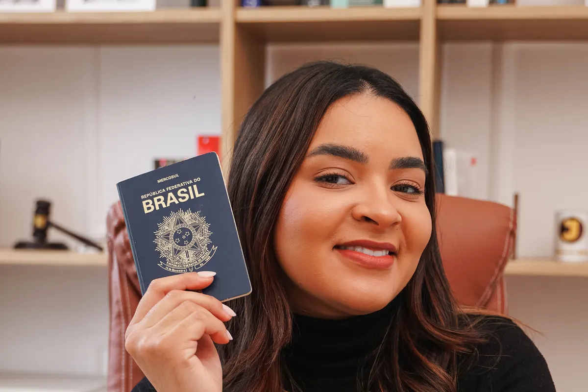 Dra. Thamyres Farias de Santana com um passaporte brasileiro, no escritório do Porto